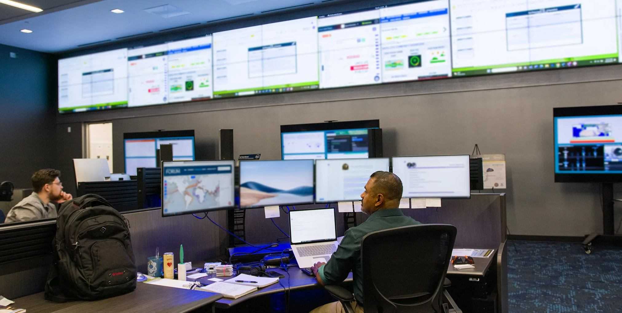 Space ISAC operations center with a wall of monitoring screens and analysts at workstations.